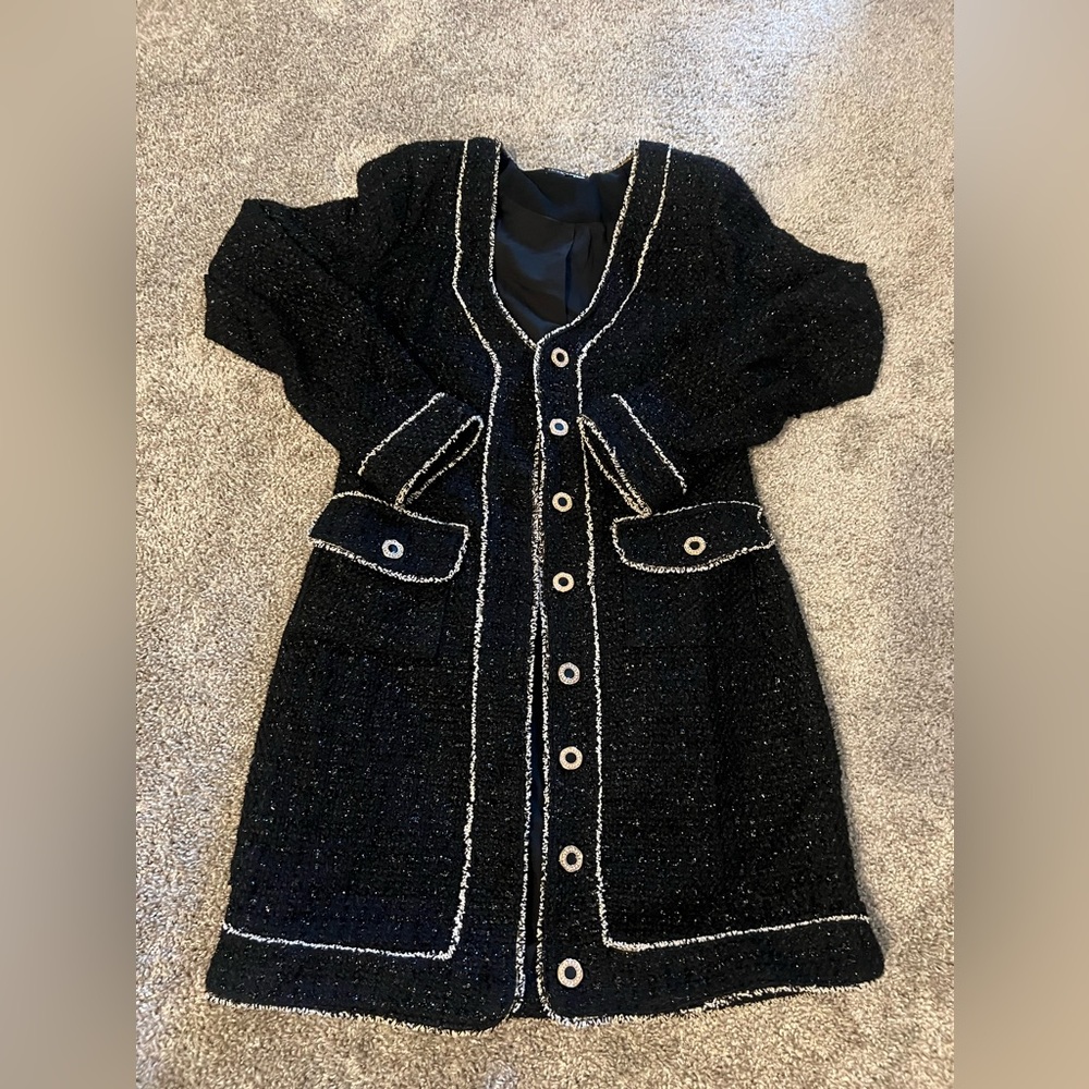 This is a black tweed dress featuring white trim accents along the edges.